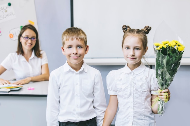 Prachtige kinderen schoolkinderen met bloemen voor de leerkrachten op school op vakantie