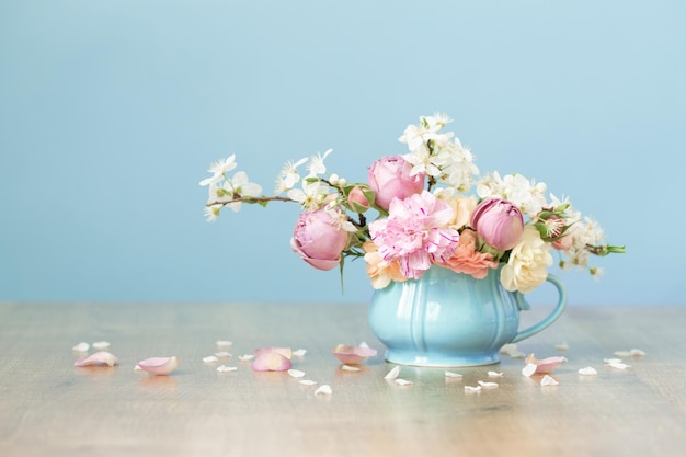 Prachtige lentebloemen in vintage beker in pastelkleuren op blauwe achtergrond