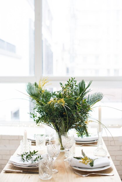 Prachtige lentetafel met groene bladeren en mimosa takken