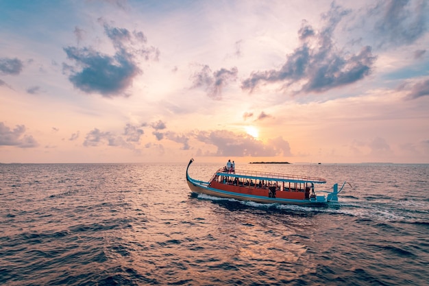 Prachtige Maldivische boot Dhoni op tropische blauwe zee, die toeristen meeneemt naar een cruise bij zonsondergang.