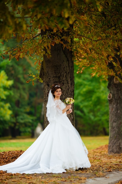 Prachtige stijlvolle blonde bruid in vintage witte jurk wandelen in het park