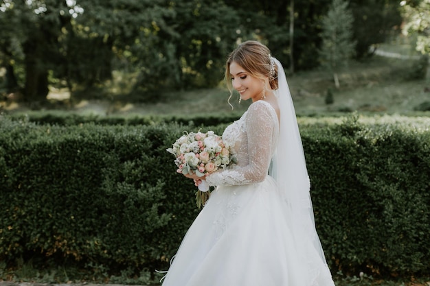 Prachtige stijlvolle bruid in vintage witte jurk wandelen in het park