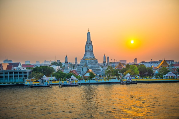 Prachtige tempel van de dageraad of Wat Arun en Thonburi westelijke oever van de Chao Phraya-rivier bij zonsondergang met stralende zon Bangkok Thailand