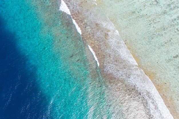 Prachtige tropische witte zeegolven van bovenaf gezien over koraalrif rotsachtige kust blauwe oceaanlagune