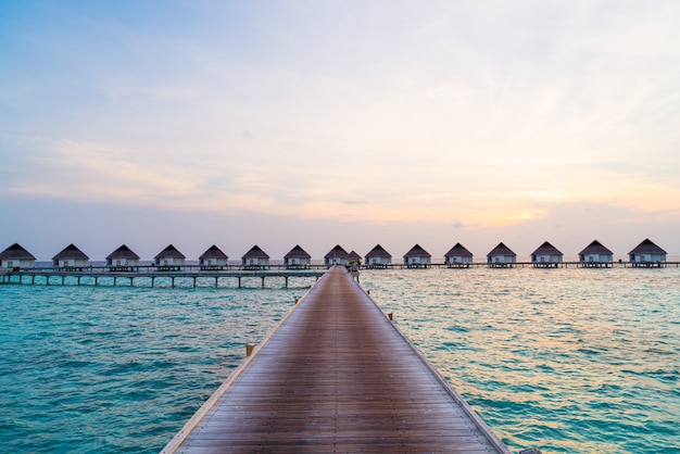 Prachtige tropische zonsondergang over eiland van de Maldiven met water bungalow in hotel resort