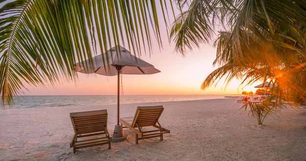 Prachtige tropische zonsondergang strand zee twee ligbedden parasol onder palmbladeren Zomervakantie