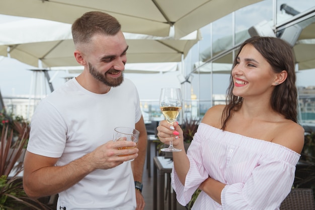 Prachtige vrouw lacht, genietend van het drinken van wijn met haar vriend in de bar op het dak