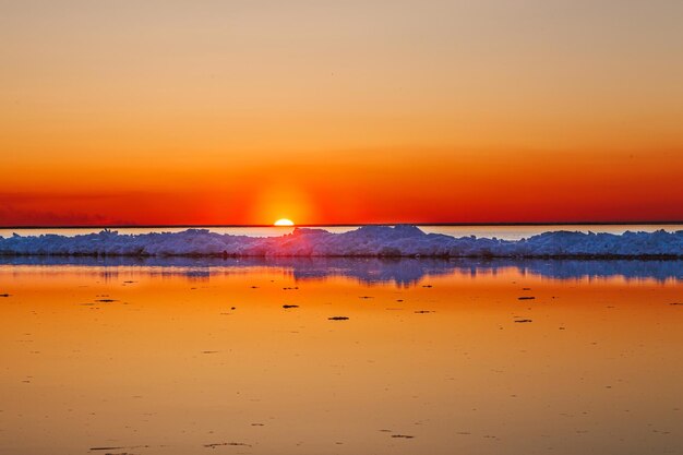 Prachtige winterzonsondergang aan zee met ijsberg