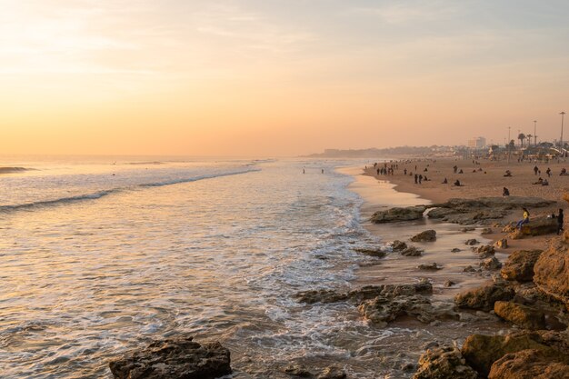 Prachtige zonsondergang in de atlantische oceaan in portugal en gezinnen genieten op het strand op een zonnige dag