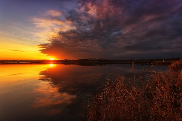 Prachtige zonsondergang op het meer met wolken en reflecties in het water