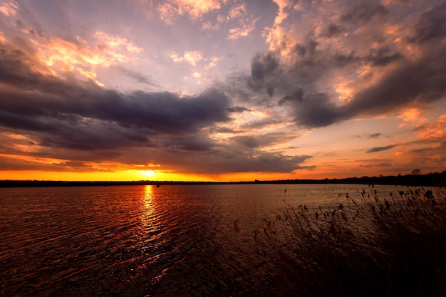 Prachtige zonsondergang op het meer met wolken en zonnestralen