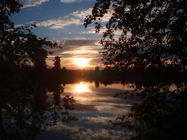 Prachtige zonsondergang op het meer Zonsondergang weerspiegeld in de waterblauwe en oranje lucht met wolken