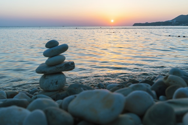 Prachtige zonsondergang op zee en balancerende piramide van stenen