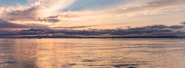 Prachtige zonsondergang over zee met weerspiegeling in water majestueuze wolken in de lucht banner lang formaat