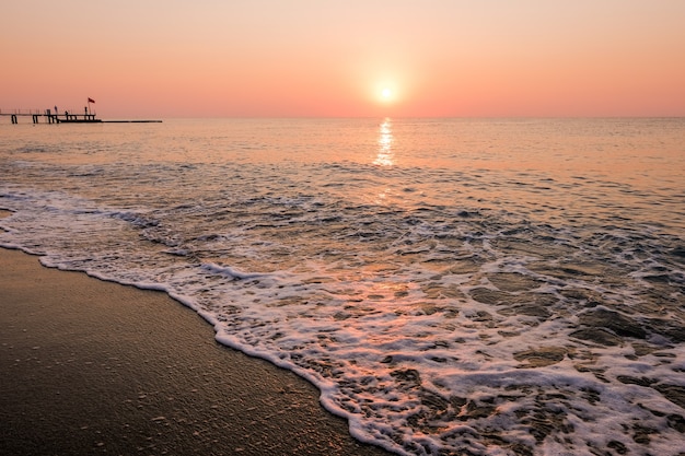 Prachtige zonsondergang zonsopgang strand met roze lucht en pier. Reizen, ontspannen en meditatie concept