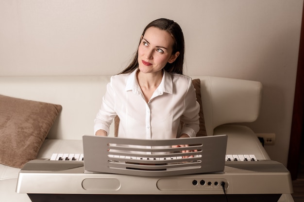 Practice playing the synthesizer, frontal portrait of a woman on an electronic piano