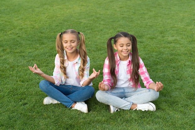 Practicing mudras during meditation Happy children do meditation on green grass Small girls enjoy meditation practice Meditation and mantra Meditate for concentration Zen and enlightenment