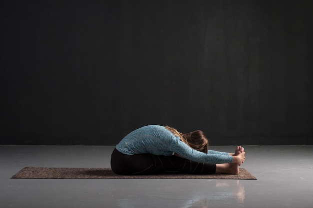 Practicing yoga doing paschimottanasana exercise Seated forward bend pose