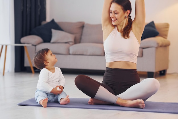 practicing yoga mother with her little daughter is at home together