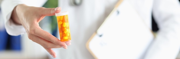 Practitioner holds jar of pills in his hand