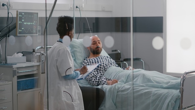 Practitioner specialist with black skin checking sick man writing disease treatment