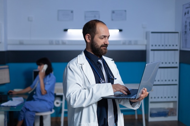 Practitioner using modern laptop for medical work at night