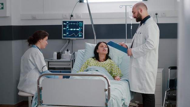 Practitioners doctors monitoring sick woman writing sickness treatment