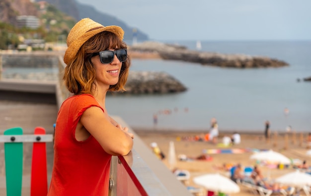 Praia da Calheta in summer young tourist girl in red dress on the beach Madeira Portugal