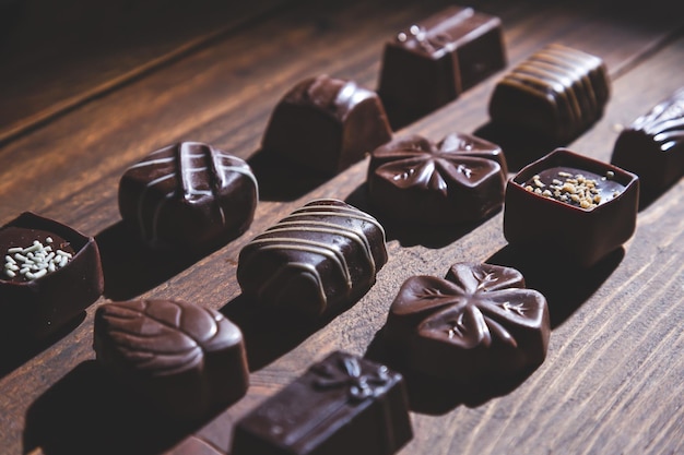 Pralines on wooden base deep shadows close up sweet and chocolate concept