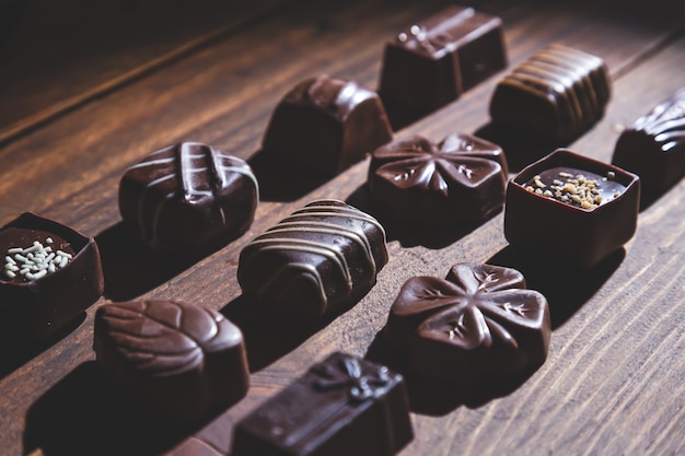 Photo pralines on wooden base, deep shadows, close up. sweet and chocolate