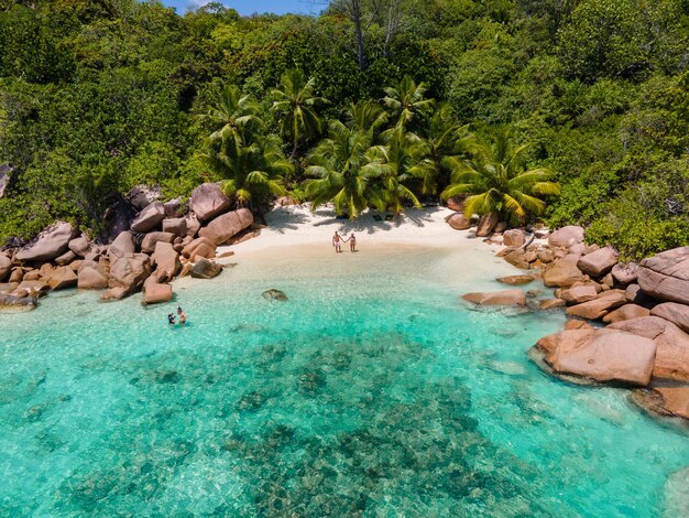 Praslin seychelles tropical island with withe beaches and palm trees couple men and women mid age on vacation at the seychelles visiting the tropical beach of anse lazio praslin seychelles drone view