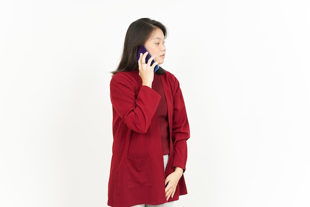 Praten over de telefoon van een mooie Aziatische vrouw die een rood shirt draagt dat op een witte achtergrond wordt geïsoleerd