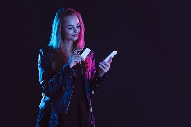 Pratende telefoon met boodschappentassen en kaart Portret van een jonge vrouw in neonlicht op dark