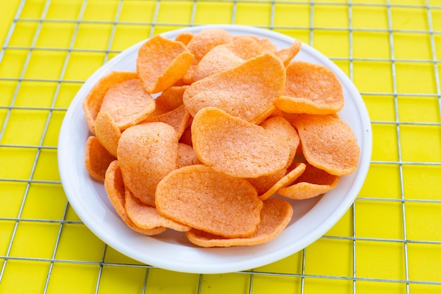 Photo prawn crackers in white plate on yellow background. shrimp crispy rice snack