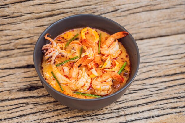 Prawn and lemon grass soup with mushroomstom yam kung thai food in wooden background top view