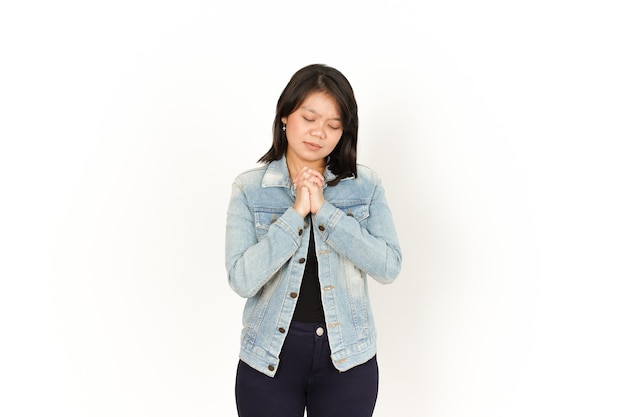 白で隔離のジーンズジャケットと黒のシャツを着て美しいアジアの女性のジェスチャーを祈る