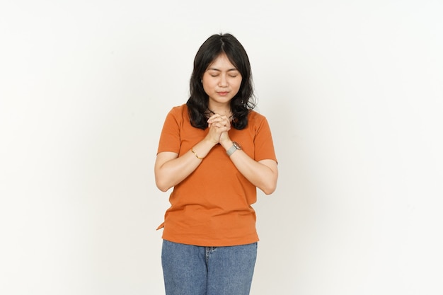 Pray gesture of beautiful asian woman Wearing orange Tshirt isolated on white background