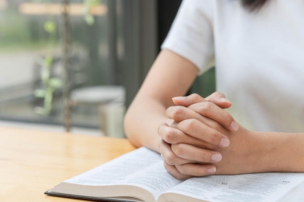 祈りと宗教の概念女性のキリスト教徒の手は折りたたまれ、霊性を祈るために聖書を読みます