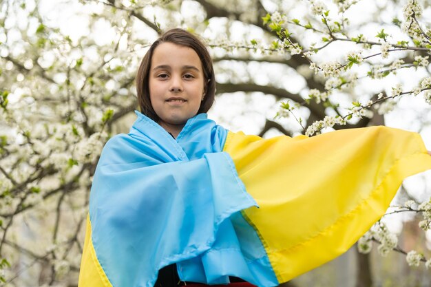 Pray for Ukraine. Child with Ukrainian flag. little girl with the flag of Ukraine waving national flag praying for peace. Happy kid celebrating Independence Day.