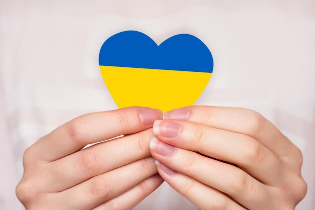 Photo pray for ukraine female hands hold a heart with the flag of ukraine ukraine's independence day