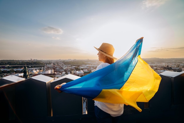 Prega per la donna ukrainexaa sta con la bandiera nazionale ucraina e la sventola pregando per la pace al tramonto a lvivxaa simbolo dell'indipendenza e della forza del popolo ucraino