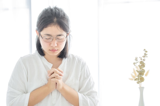 사진 기도하는 소녀는 신을 숭배하고 집에서 코로나바이러스 코비드-19를 위해 기도합니다. 가정예배, 온라인교회, 손기도, 가정예배