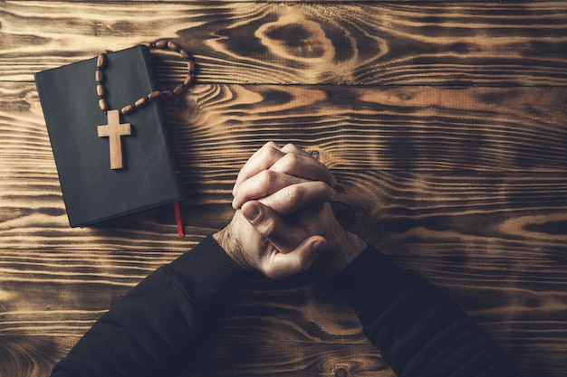 Photo prayer man hand cross on holy bible on wooden table