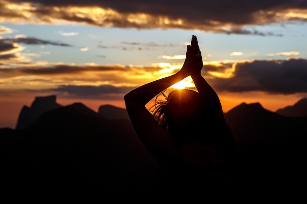 Prayer. Silhouette girl prays at sunset.