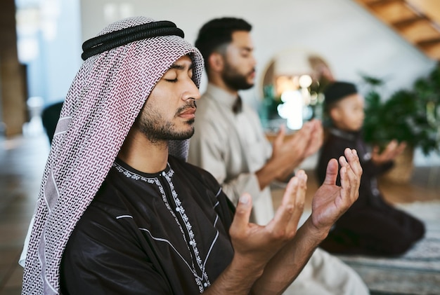 Prayer with a thankful heart shot of a group of muslim male\
family members praying together