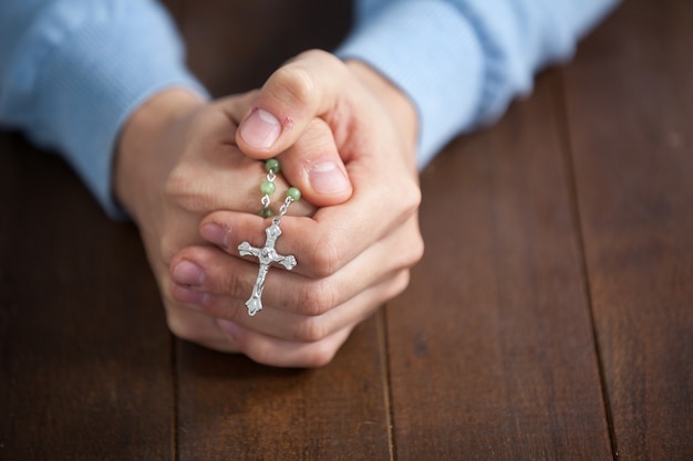 Praying hands of man with a rosary