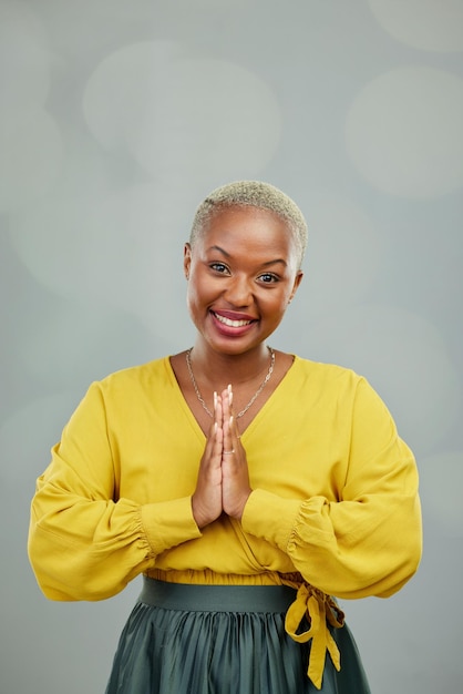 Praying hands thank you and portrait of happy woman in studio with gratitude sign on wall background Face together hand and smile by female person showing space prayer and worship emoji icon