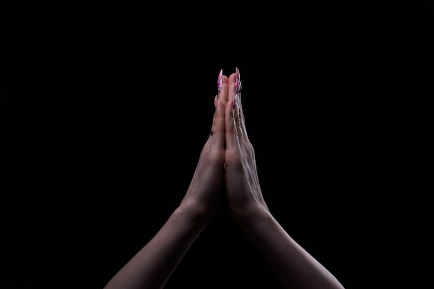 暗い背景に宗教と神への信仰を信じて手を祈る