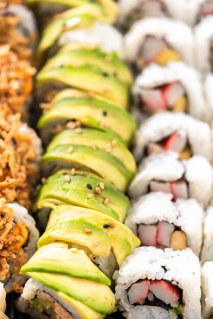 Pre-packaged variety of sushi and sushi rolls in a plastic tray.