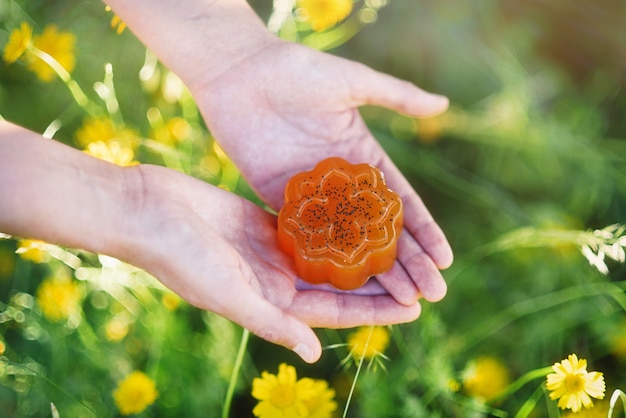 野外の花の中で女性の手にある貴重な有機石鹸